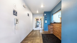 Een hotelhal met houten vloer, een receptiebalie en een telefoon aan de muur.