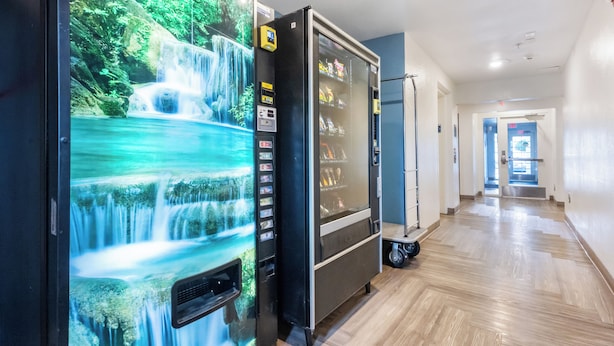 Een hal met een muurschildering van een waterval, een automaat en een schone, gepolijste vloer.