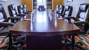 Un salón de conferencias con una larga mesa, sillas de cuero y un candelabro.