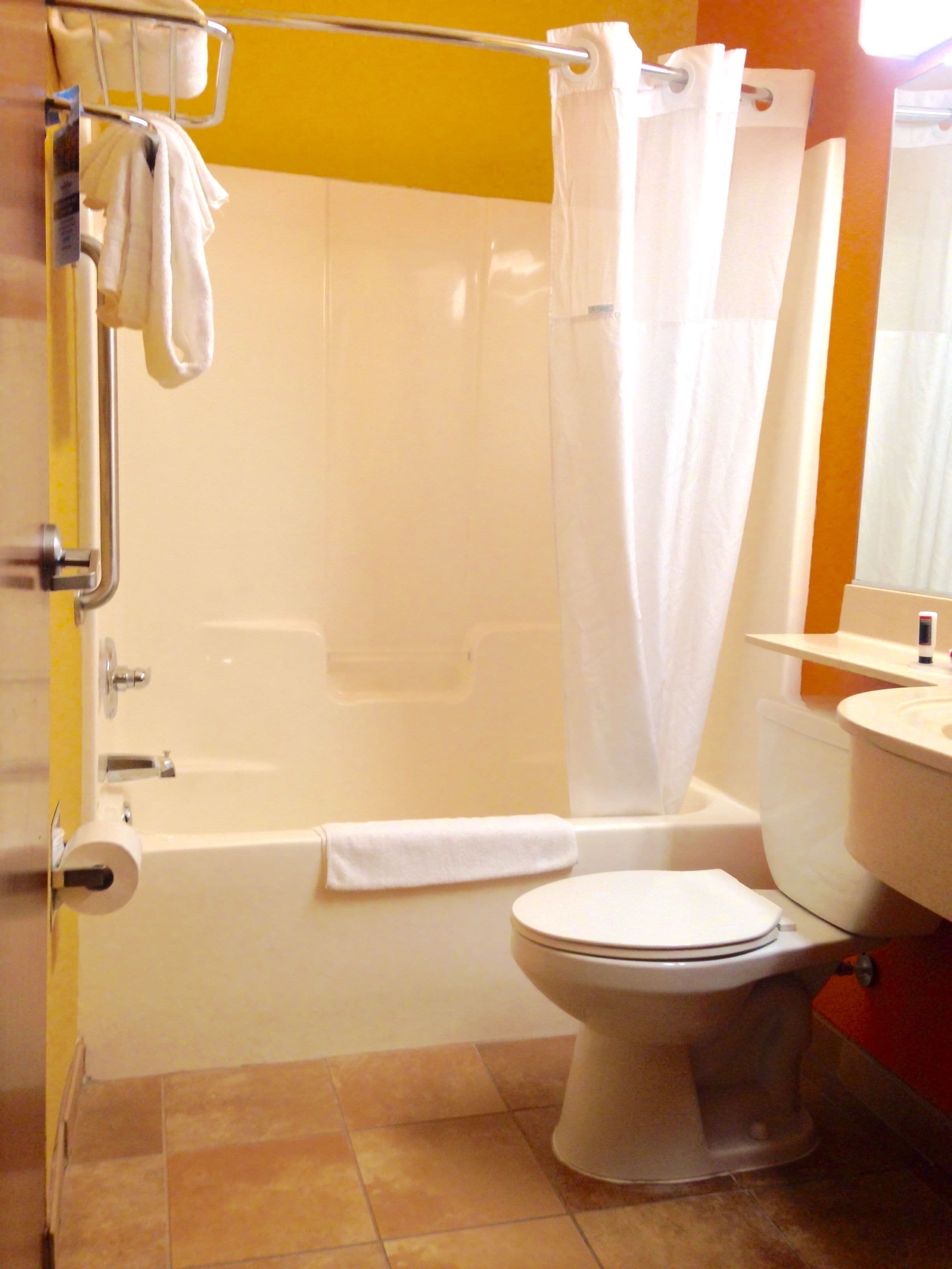 A bathroom with a bathtub, toilet, and a shower curtain.