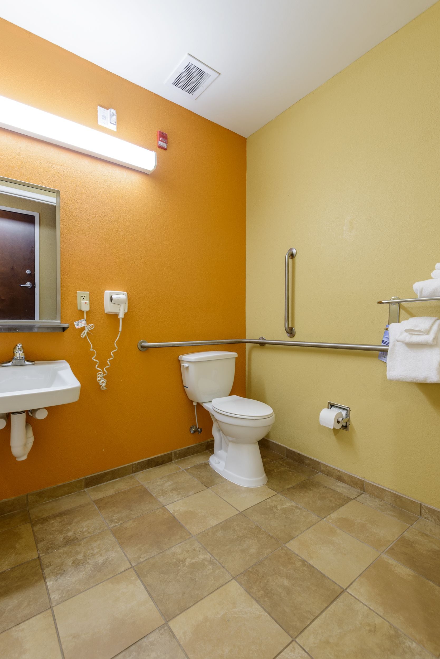 A bathroom with a white toilet, a sink, and a handrail.