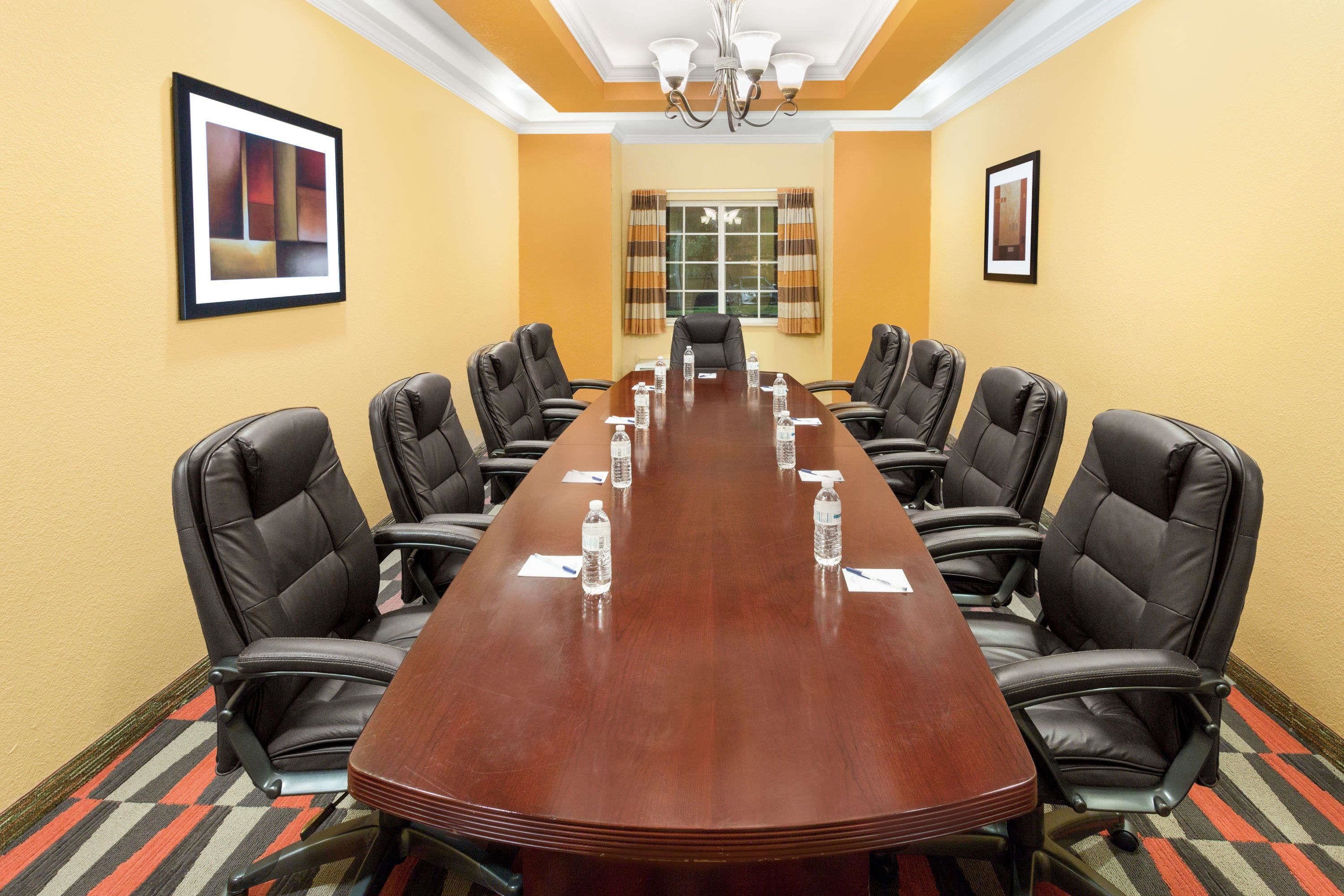 A conference room with a long table, black leather chairs, and water bottles.