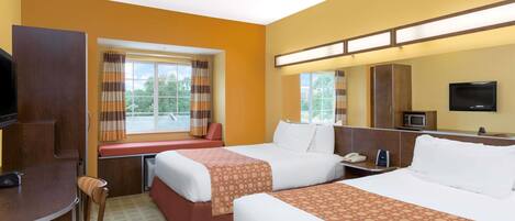Une chambre d’hôtel avec deux lits, un bureau, une chaise, une télévision et une fenêtre avec des rideaux.