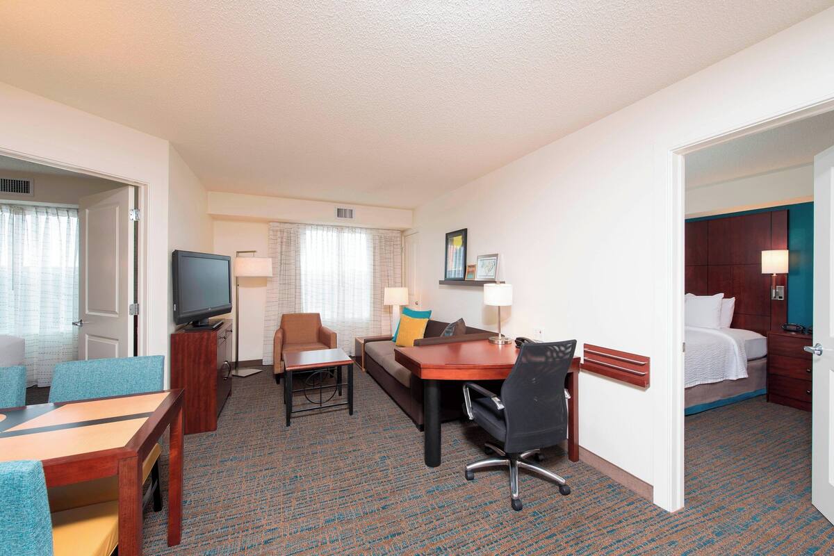 A hotel room with a bed, a desk, a chair, a television, and a window with curtains.