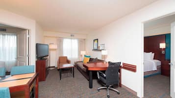 A hotel room with a bed, a desk, a chair, a television, and a window with curtains.