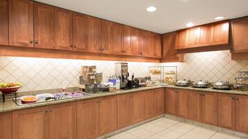 A kitchen with wooden cabinets, a granite countertop, and various appliances.