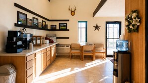 A kitchen with a coffee machine, a microwave, and a toaster. There is a dining area with a table and chairs.