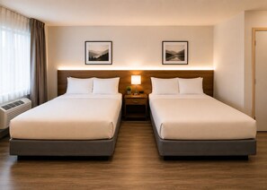 A double room with two beds, a bedside table with a lamp, and a picture on the wall.