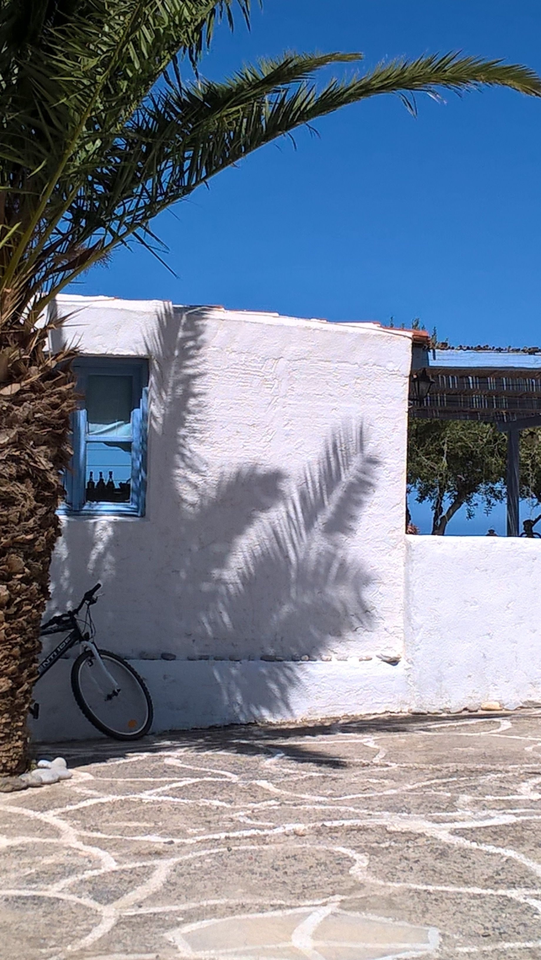 Un edificio blanco con una ventana y una bicicleta estacionada afuera.