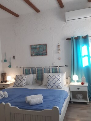 A bedroom with a bed, a nightstand, a wall-mounted shelf, a window with curtains, and a painting on the wall.