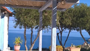 A coastal view with a pergola structure, potted plants, and trees overlooking the sea. - Bellevue Village (Malevizi)