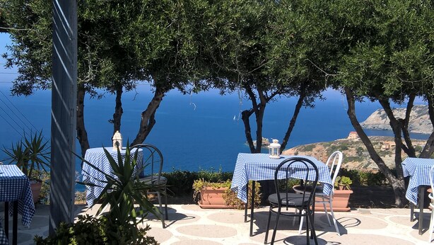 An outdoor seating area with checkered tablecloths, metal chairs, and potted plants. - Bellevue Village (Malevizi)