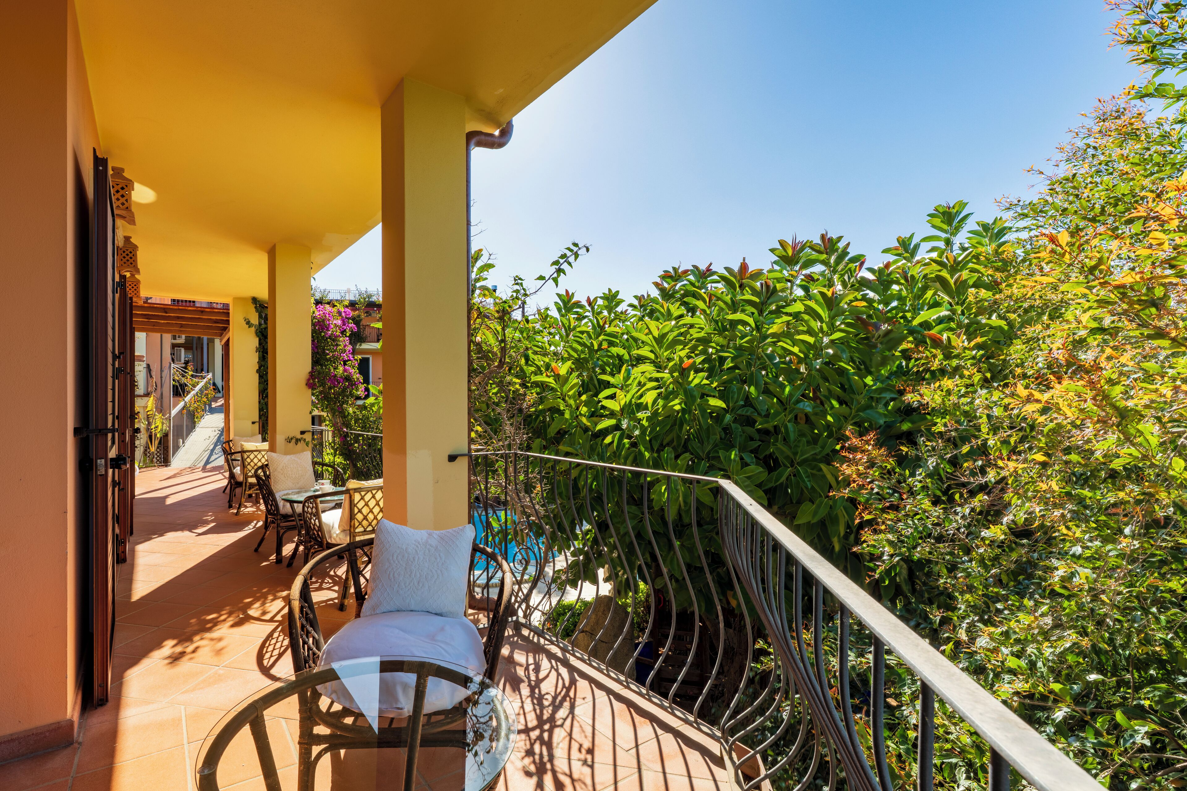 A balcony with a metal railing, a chair, and a table with a cushion.