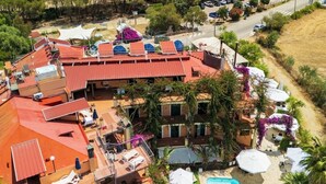 An aerial view of a hotel with a swimming pool, outdoor seating, and a view of the sea. - Aparthotel Domus De Janas Sul Mare (Bari Sardo)