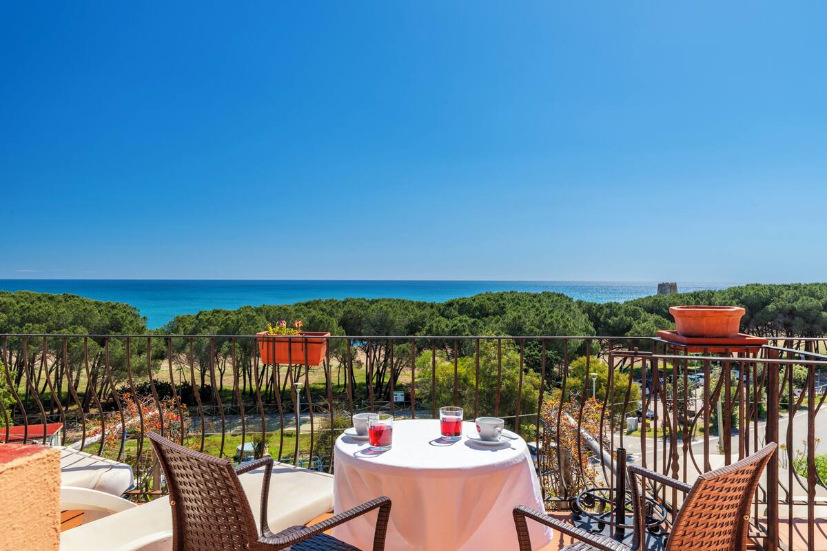 A terrace with a table set for two, overlooking a coastal view.