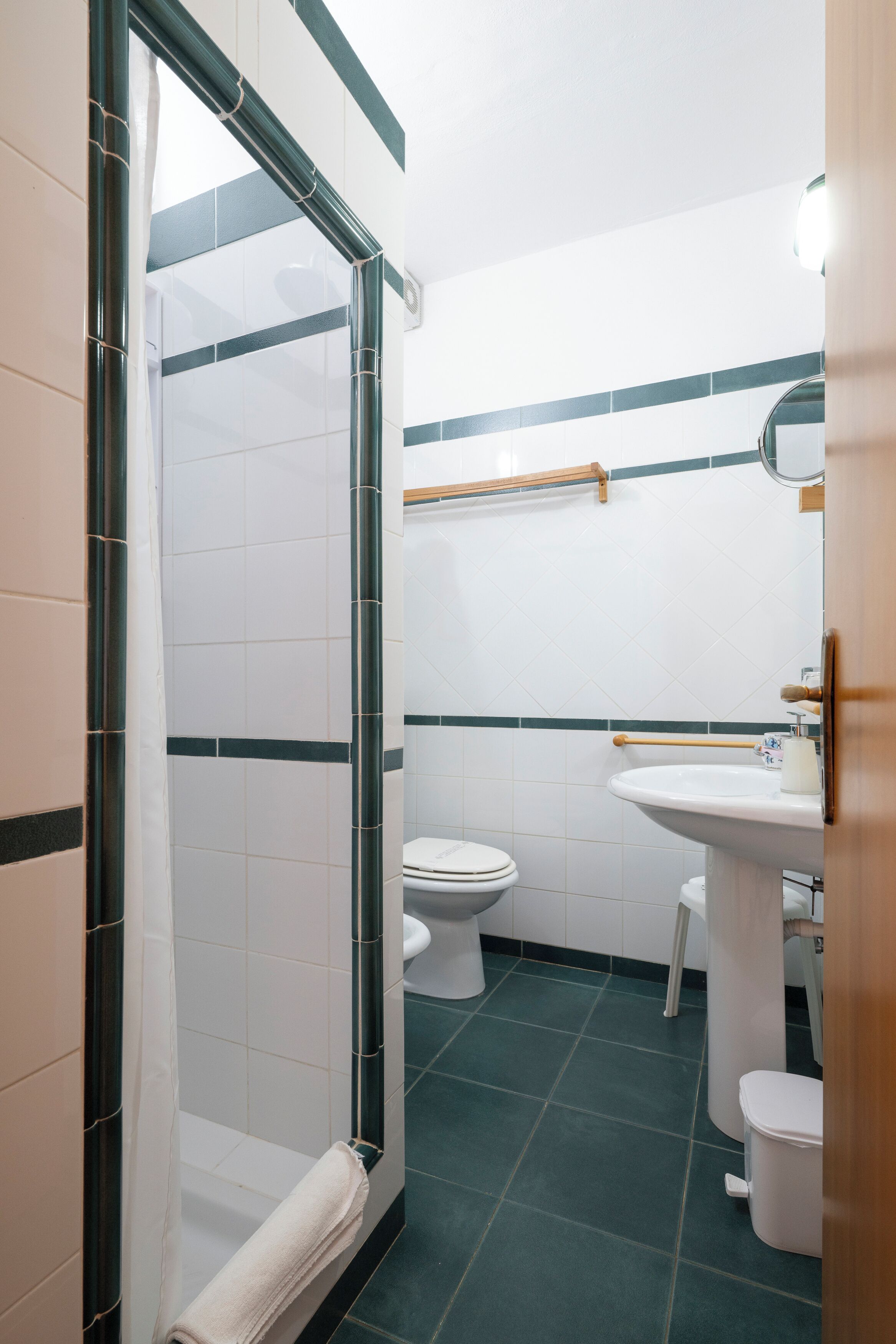 Un baño con ducha de mampara, inodoro, lavamanos y espejo.