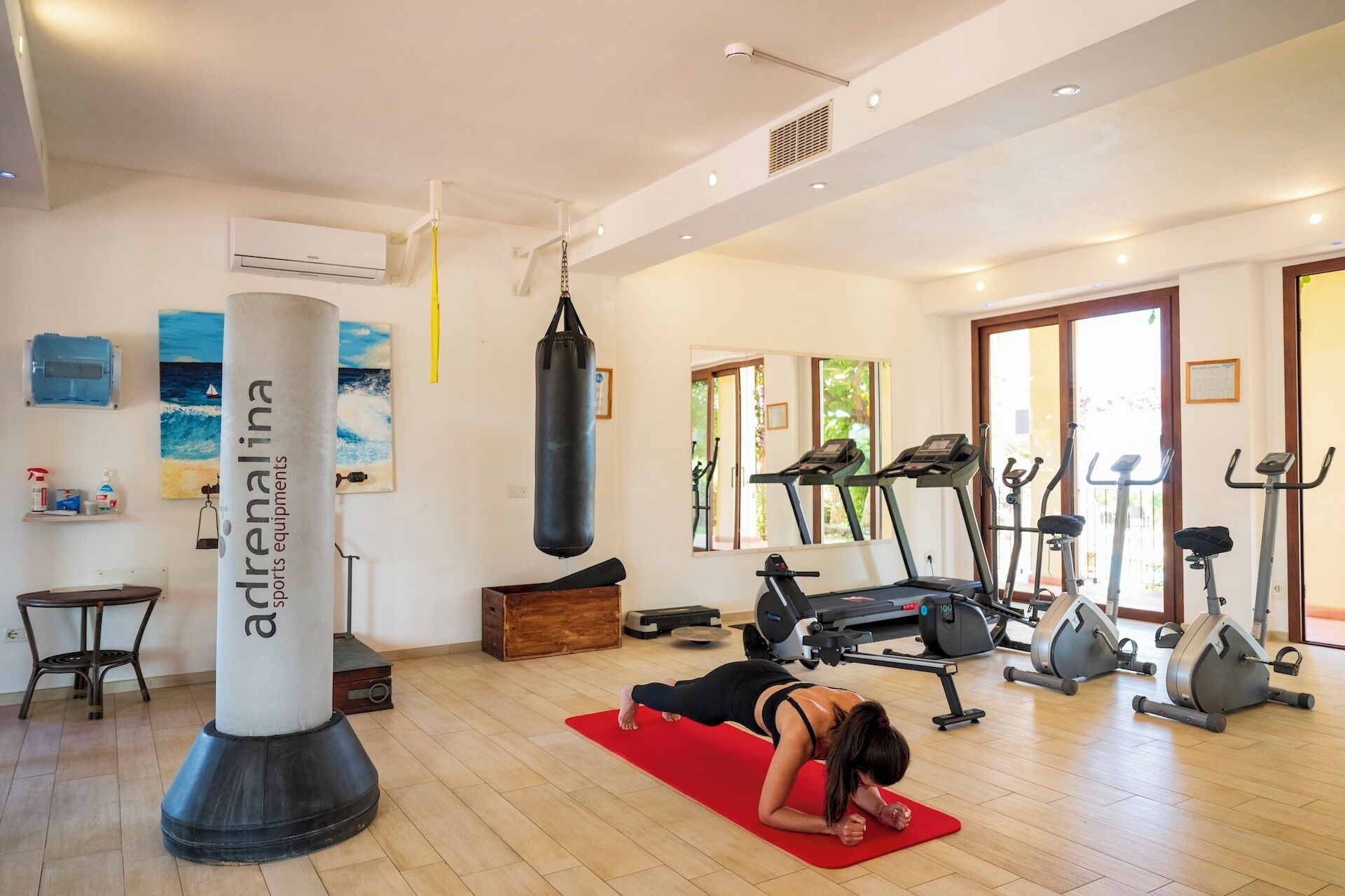 A gym with exercise equipment, a punching bag, and a yoga mat.