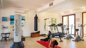 A gym with exercise equipment, a punching bag, and a yoga mat.