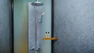 A shower with a rain showerhead, a handheld showerhead, and a handheld massager. There is a shelf with two bottles of shampoo and conditioner.