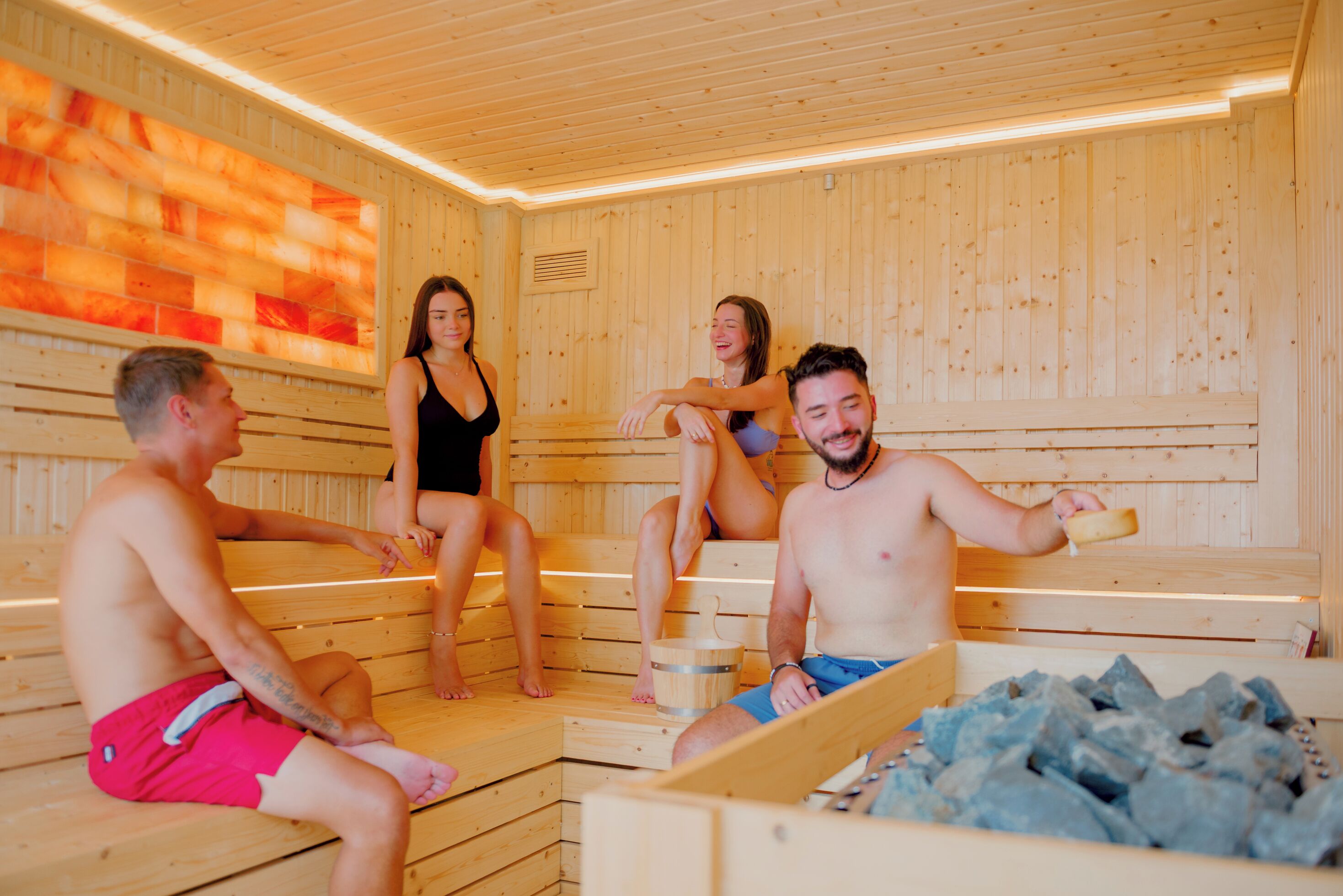 A sauna with wooden benches and a stone-filled basin.