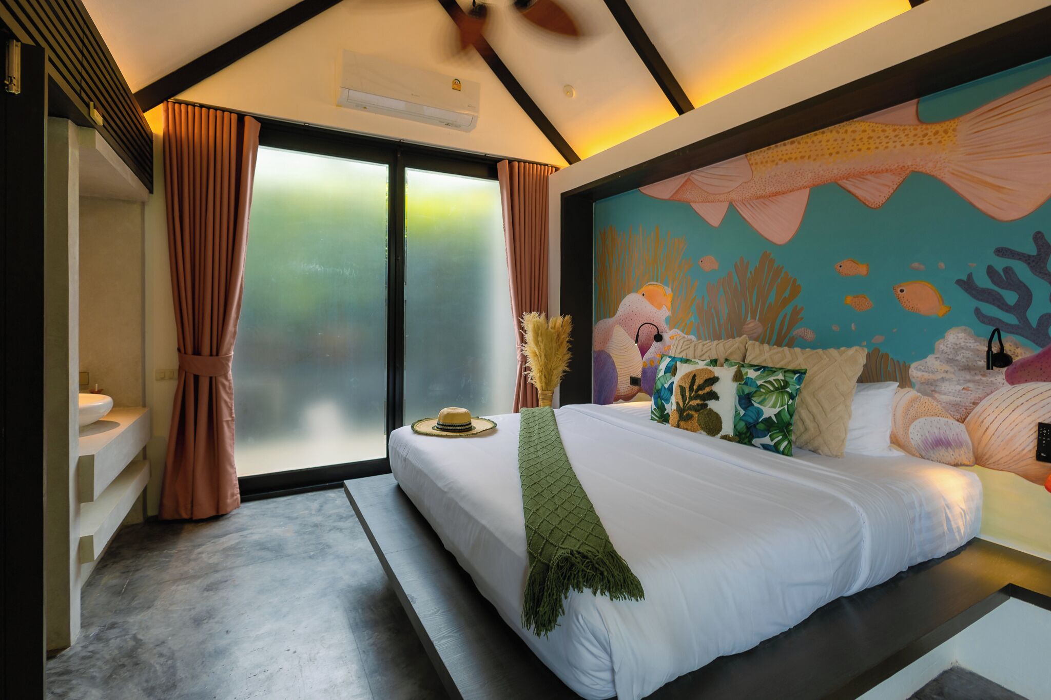 A modern bedroom with a large bed, a mural of an underwater scene, and a sliding glass door to the outside.