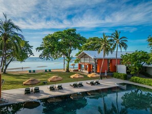Un resort con piscina, sillas de descanso y vista al océano.
