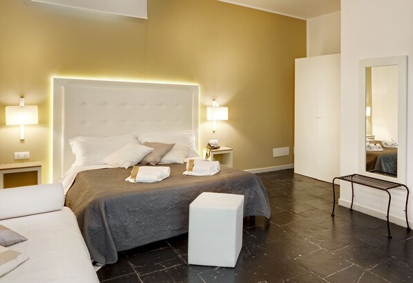 A hotel room with a large bed, bedside lamps, a wardrobe, and a mirror.