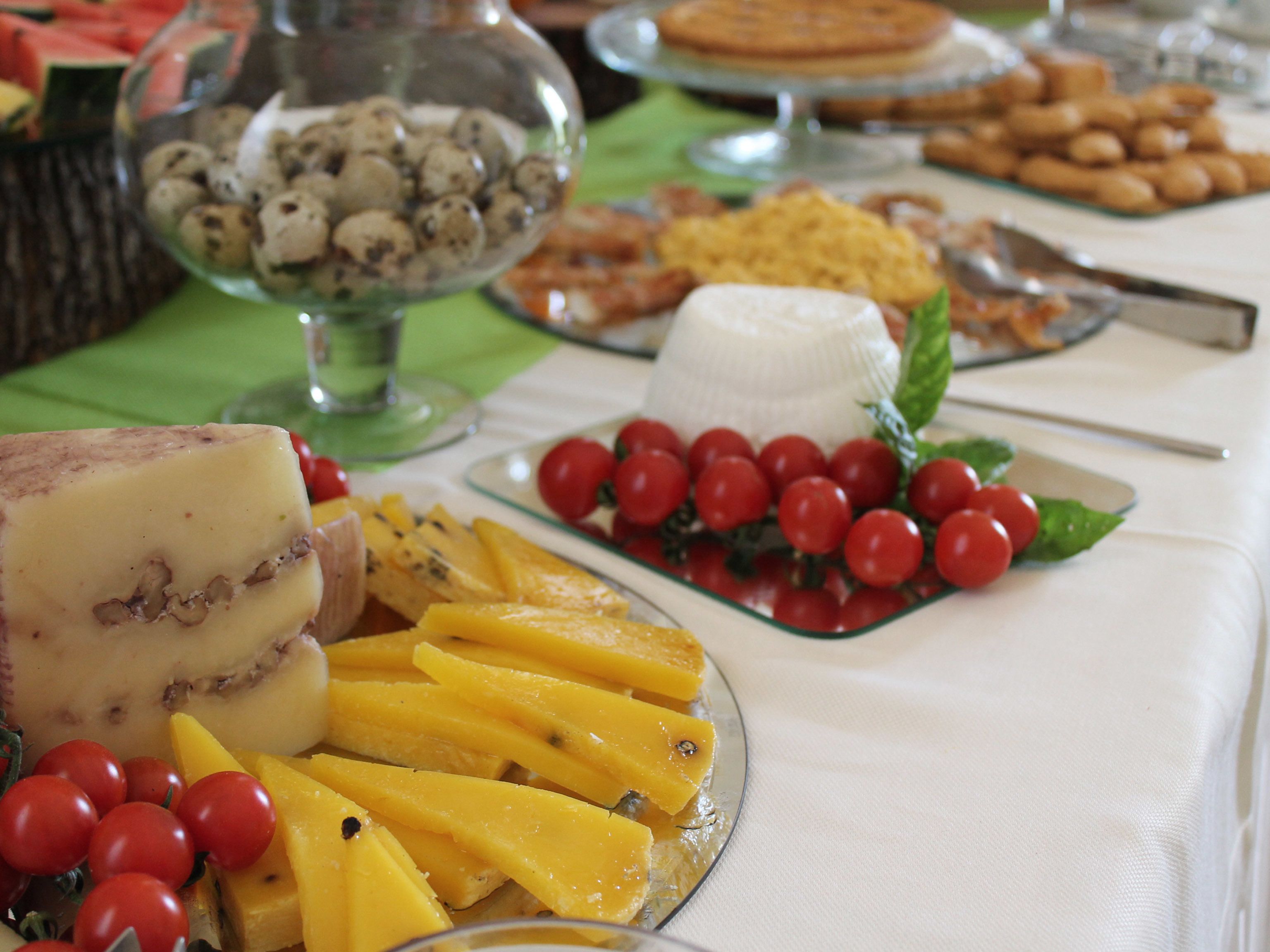Un buffet proposant une variété de plats, notamment du fromage, des tranches de mangue, des tomates cerises et d’autres mets.