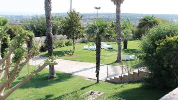 A landscaped garden with palm trees, a paved walkway, and outdoor seating.