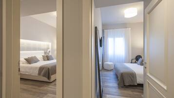 Quarto de hotel com uma cama grande, uma cama menor, uma escrivaninha e uma cadeira.