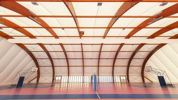 Un terrain de basket-ball intérieur avec un plafond haut et des poutres en bois.