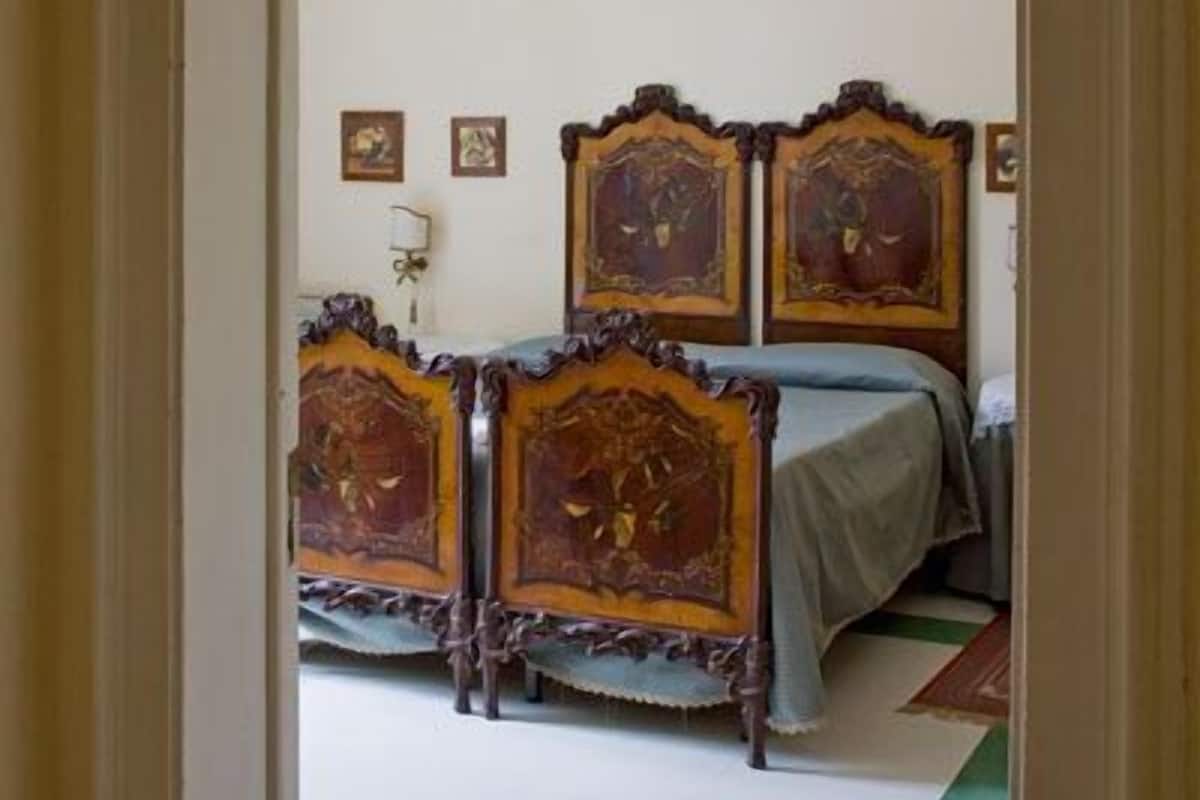 A room with a bed, two wooden headboards, and a green and white patterned floor.