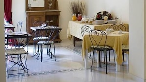 Uma sala de jantar com um candelabro, um aparador de madeira com espelho e duas molduras na parede.