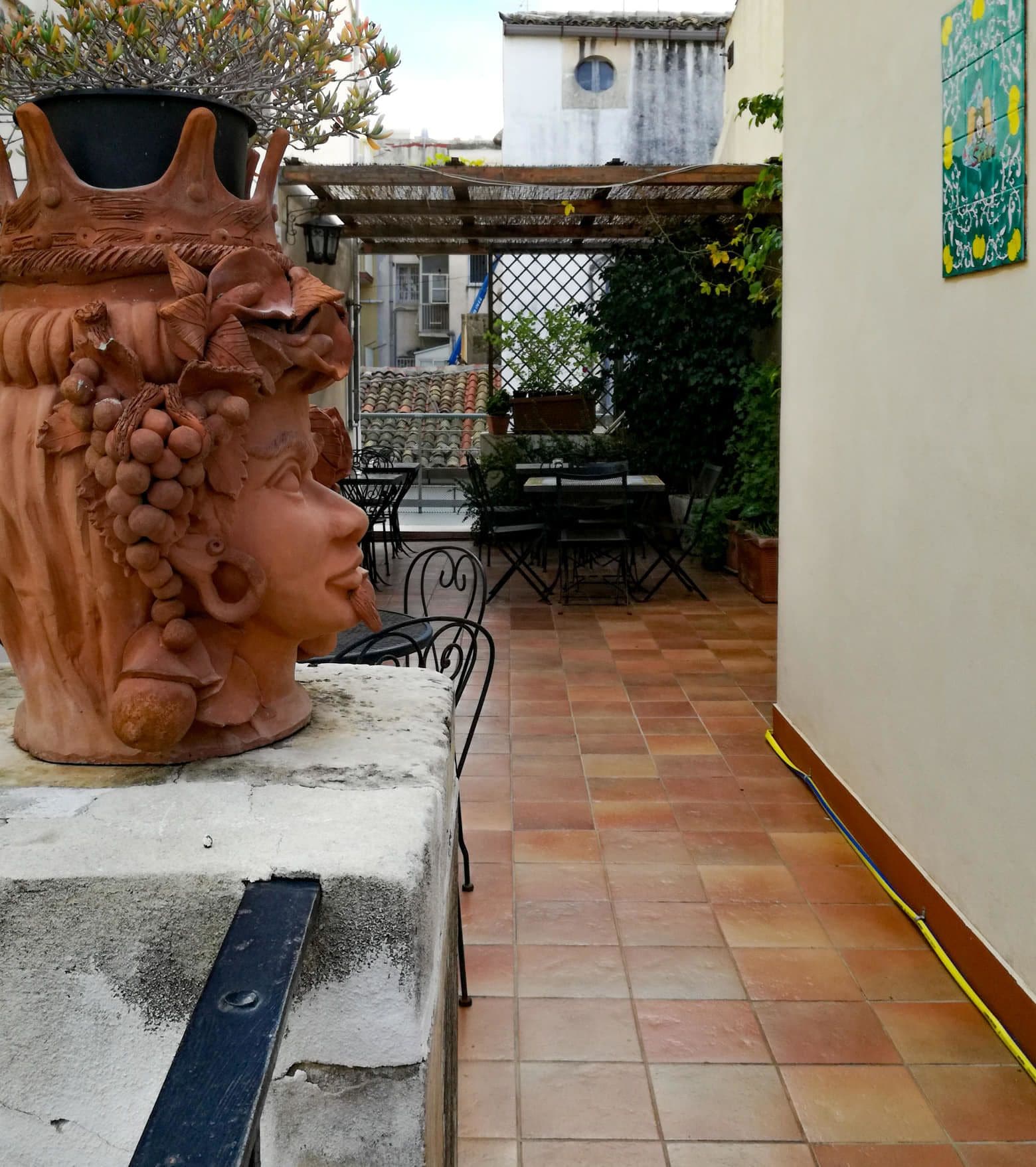 Een binnenplaats met een terracotta beeld, tuinmeubilair en een betegelde vloer.