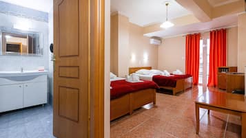 Una habitación de hotel con dos camas, una puerta de madera, un lavabo y un espejo.