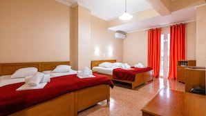 Ett hotellrum med två sängar, ett träbord och en röd gardin.