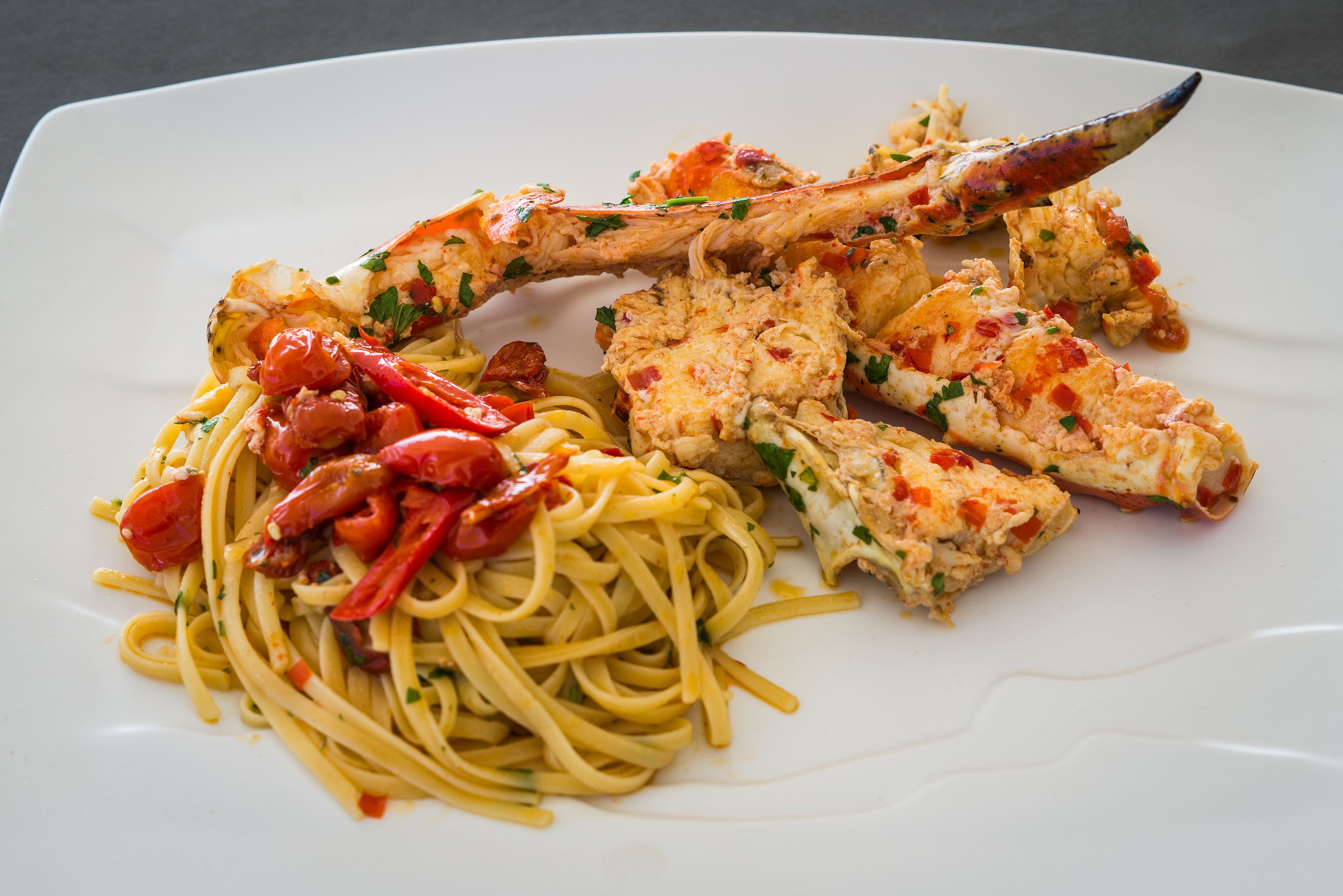 A plate of spaghetti with crab legs and a tomato-based sauce.