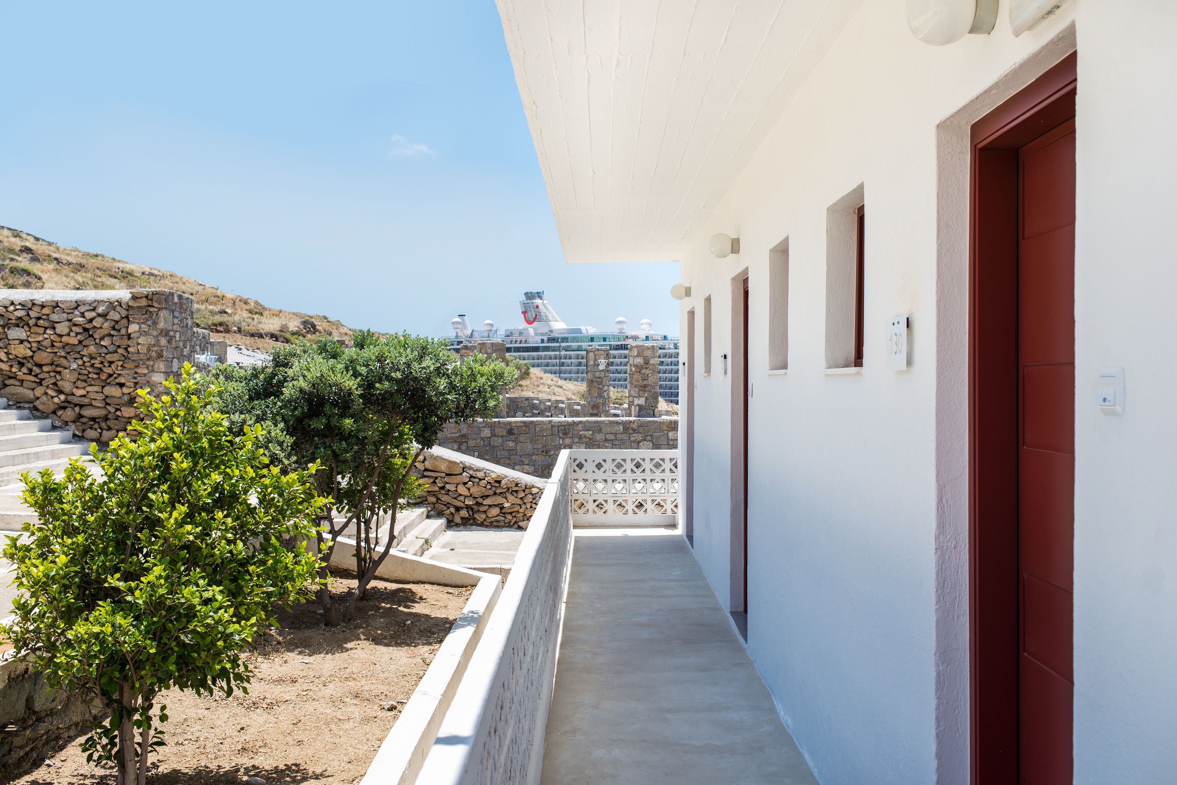 A corridor with a view of a cruise ship and a stone wall in the background.