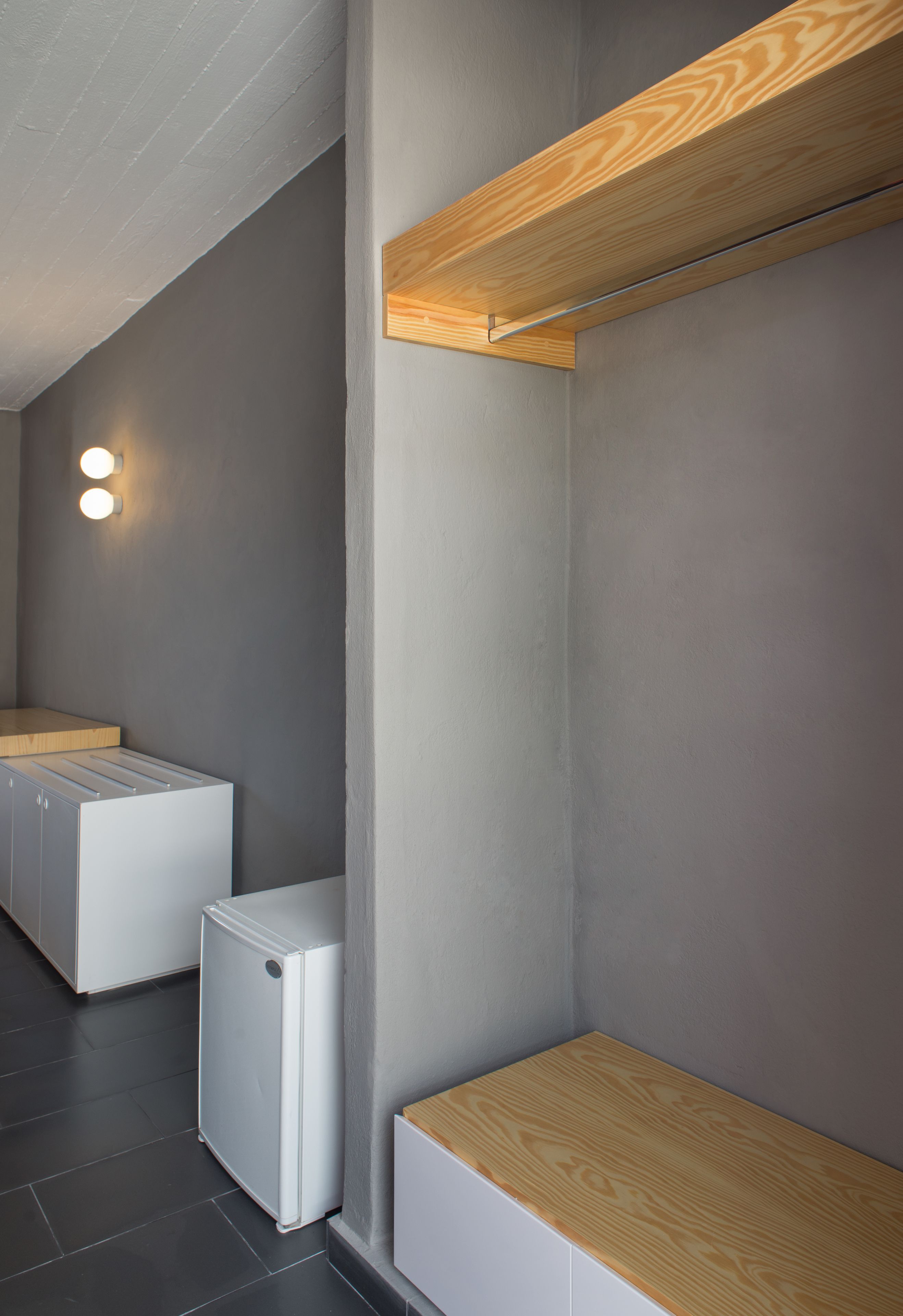 Une cuisine moderne avec des murs gris, des étagères en bois et un réfrigérateur blanc.