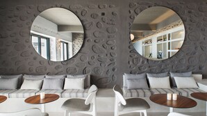 A modern interior with a stone wall, circular mirrors, a striped sofa set, and round tables.