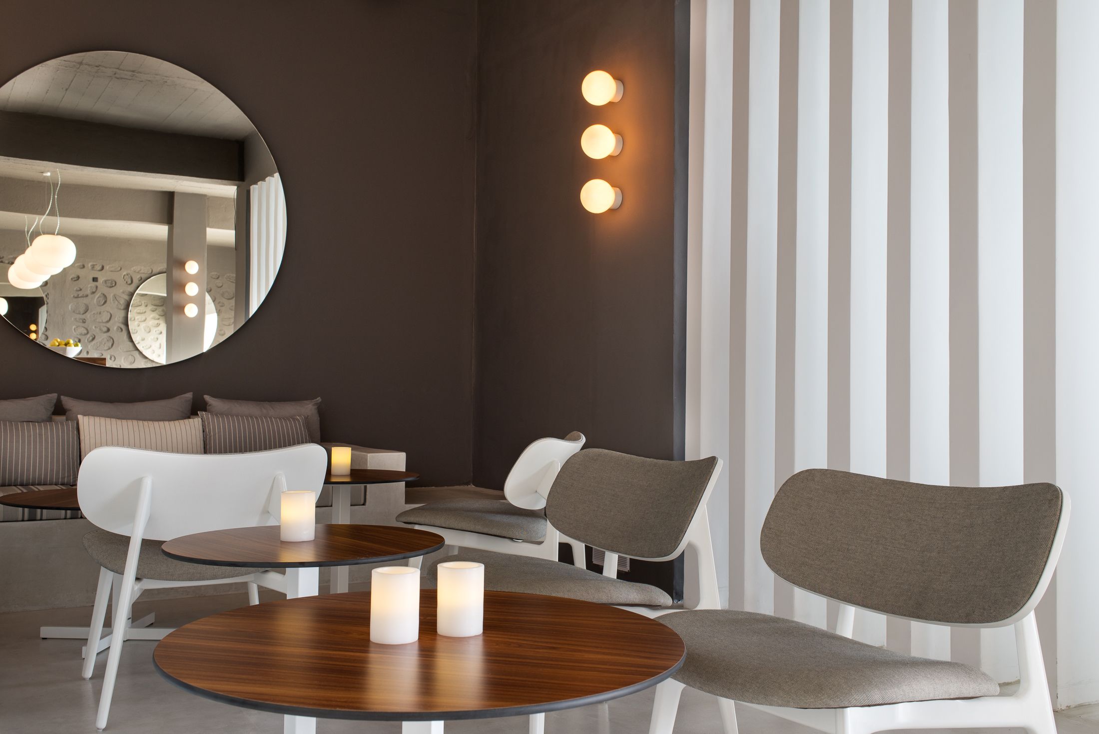 A modern interior with round tables, a sofa, and a mirror.