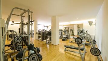 Un gimnasio con diversos equipos de ejercicio, que incluyen máquinas de pesas y pesas libres.