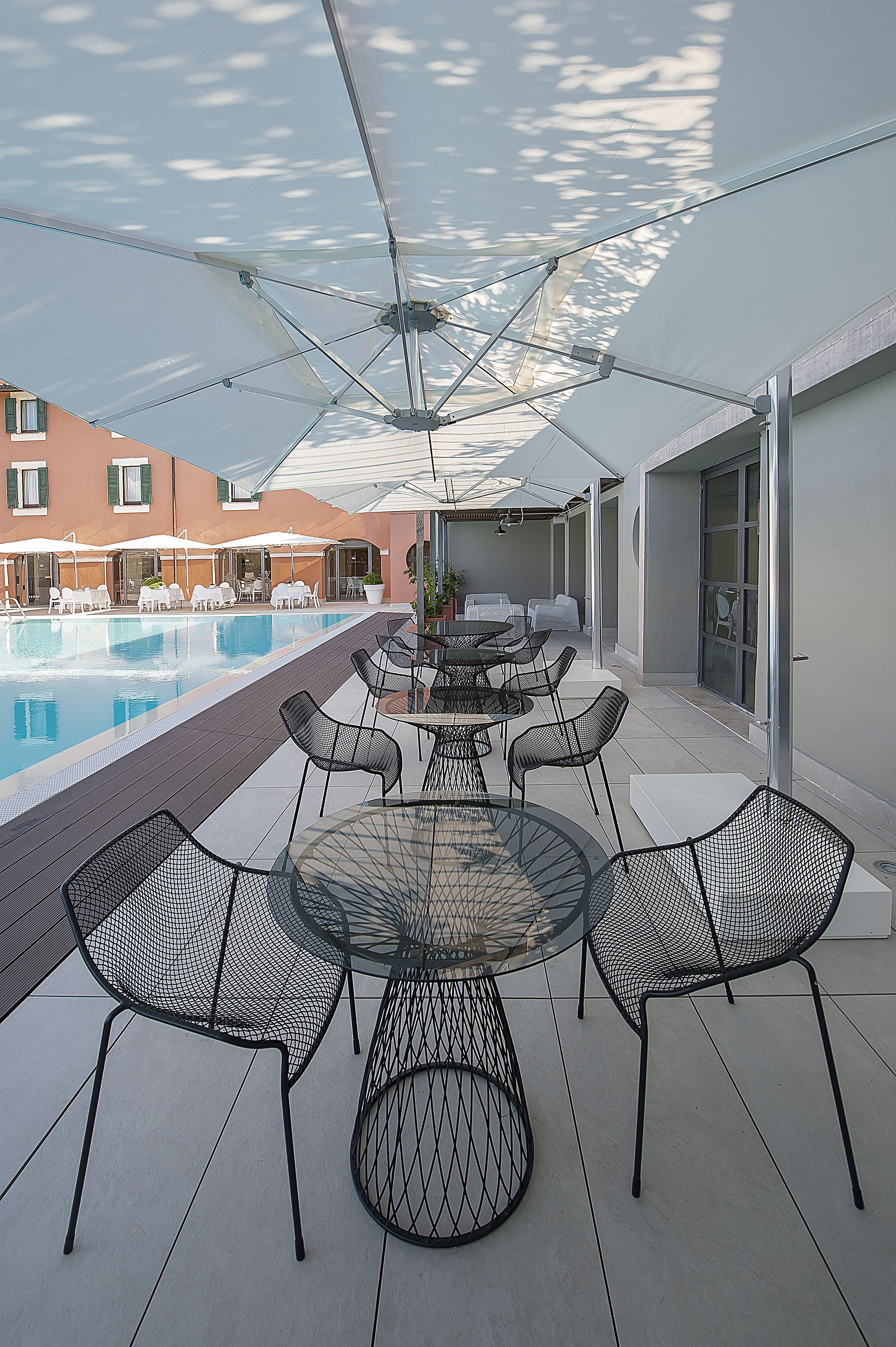 Ein Poolbereich mit Tisch und Stühlen, einem Schwimmbecken und einem Gebäude im Hintergrund.