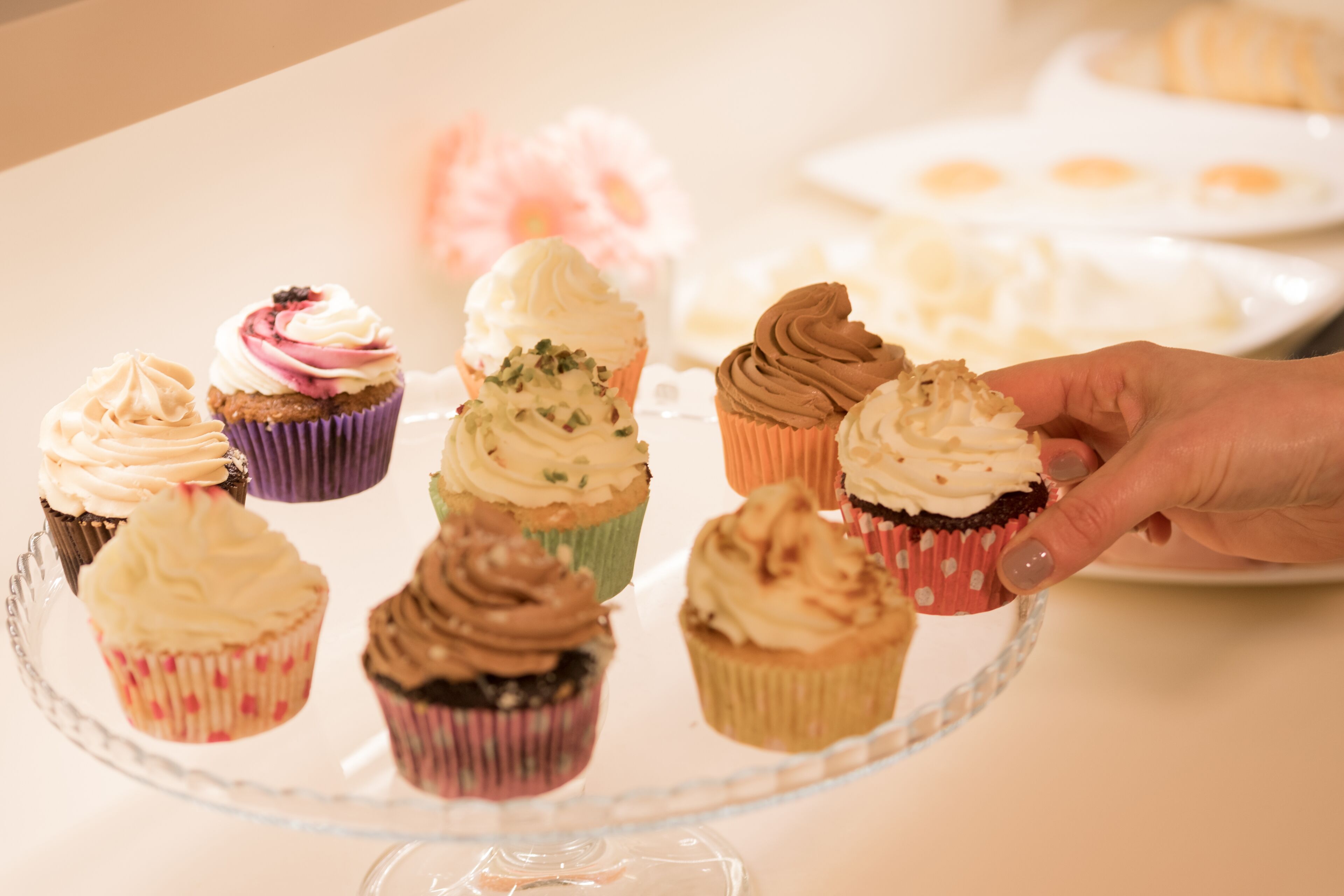 Eine Hand hält einen Cupcake mit einer Zuckerguss-Kreation.