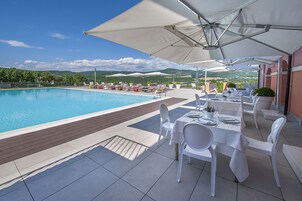 Una piscina al aire libre, sombrillas, tumbonas