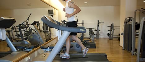 Un gimnasio con cintas de correr, bicicletas estáticas y máquinas de pesas.
