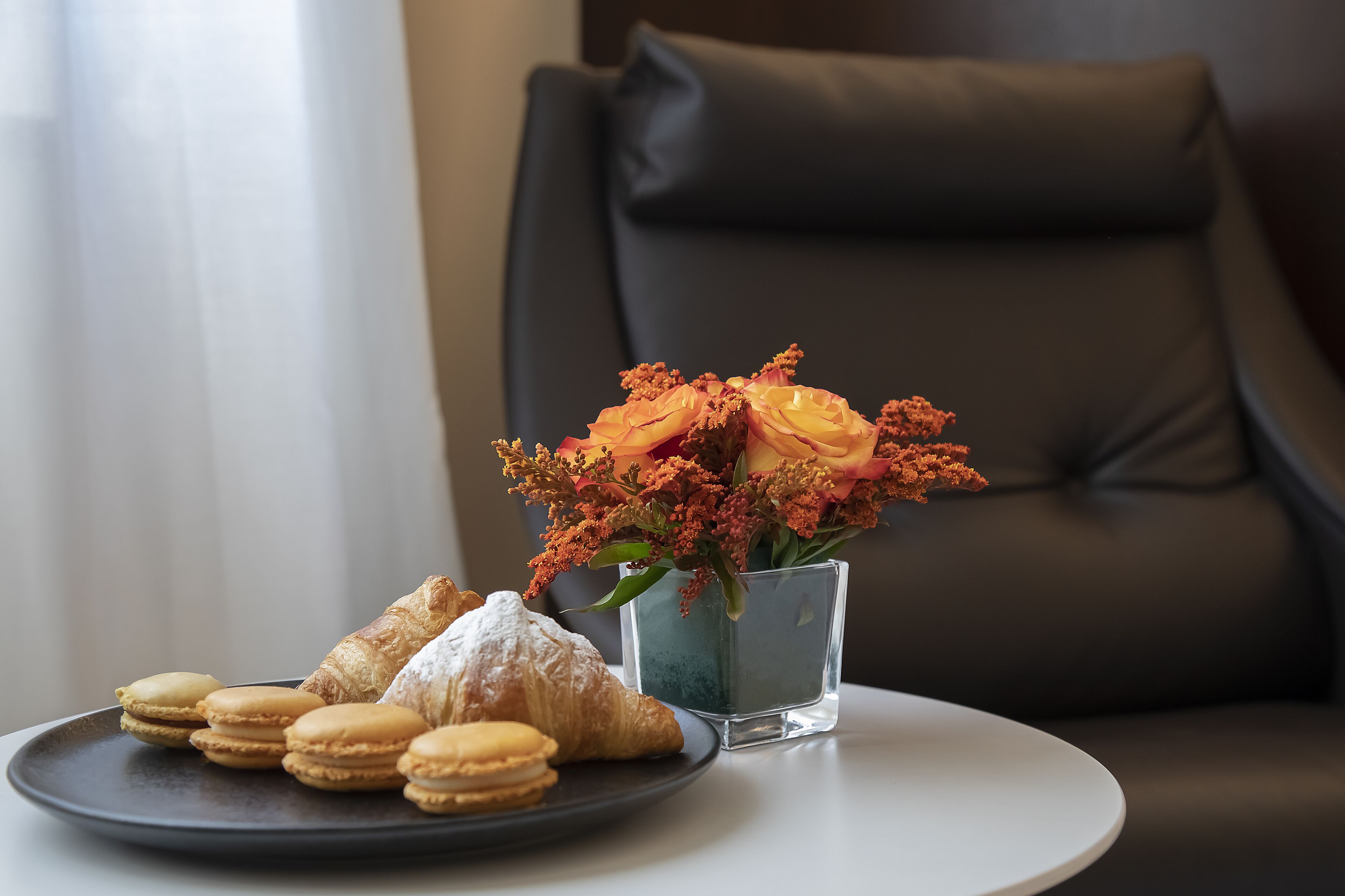 Um prato de doces e um vaso de flores sobre uma mesa.