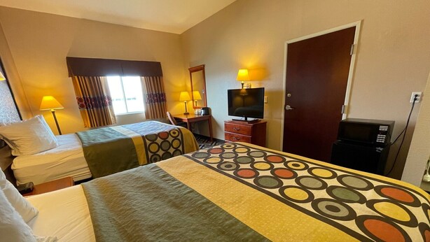 A hotel room with two beds, a TV, a desk with a lamp, a door, and a microwave. - Super 8 by Wyndham Rolla (Rolla)