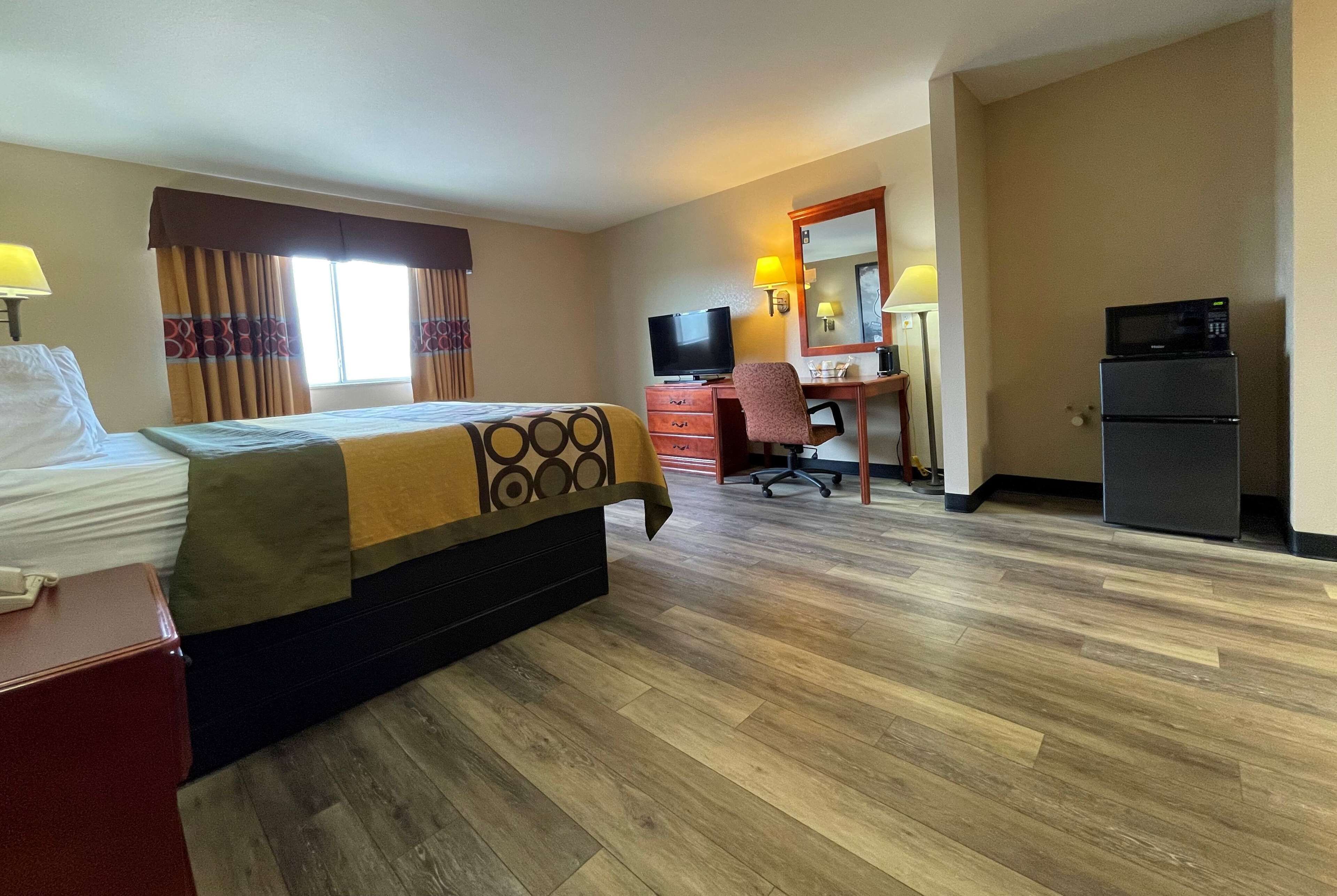 Habitación de hotel con cama, escritorio, televisor y refrigerador.