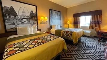 A hotel room with two beds, a desk, a chair, and a large framed picture on the wall.